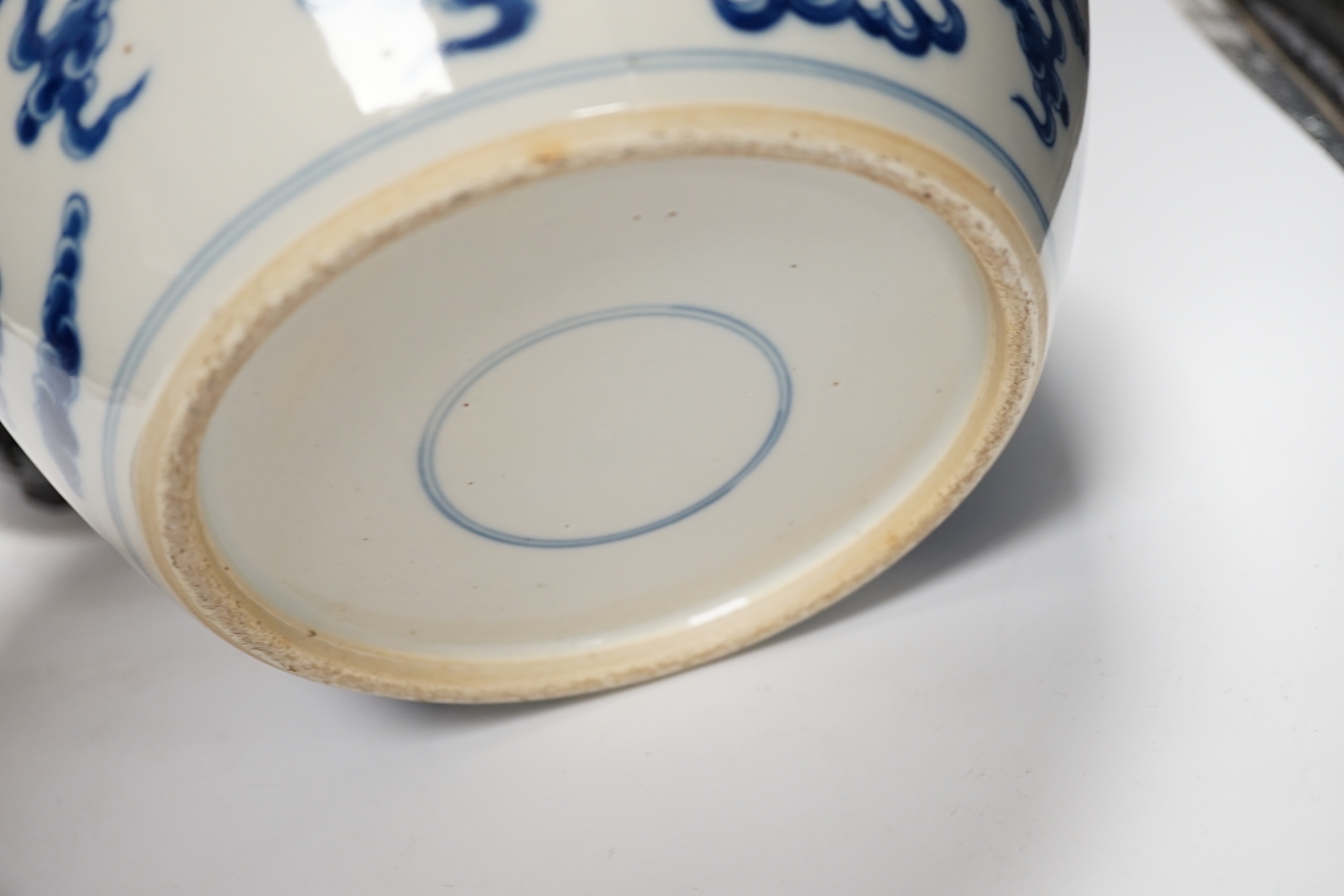 A large Chinese blue and white jar decorated with dragons chasing the flaming pearl together with unassociated carved wood lid and stand, 35cm high